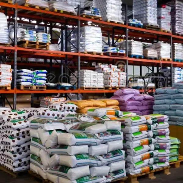 Stacks of expensive store-bought fertilizer bags in a warehouse representing the high cost and time spent on traditional gardening without a smart composter.